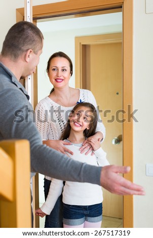 Happy man standing at doorway and inviting guests to come inside. Focus on girl