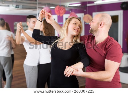Group of happy young adults dancing salsa in dance club