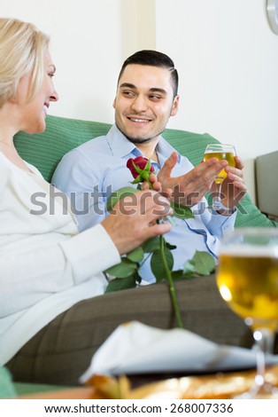 Handsome guy and mature woman drinking wine and smiling indoor