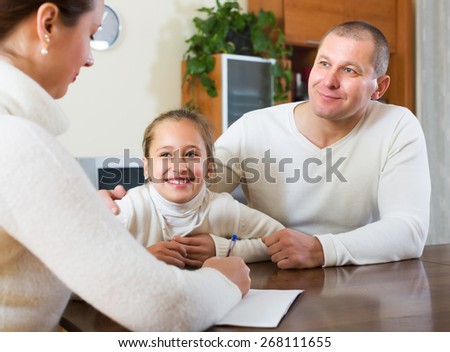 Parent and smiling daughter talking with employee in home
