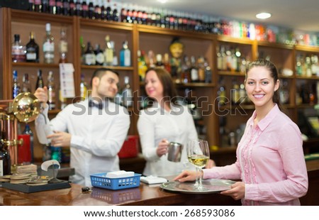 Happy waitress and barmen working in modern bar