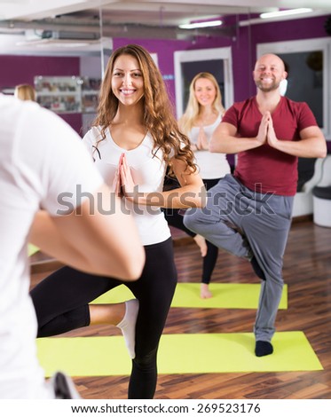Happy young people studying new position at yoga school