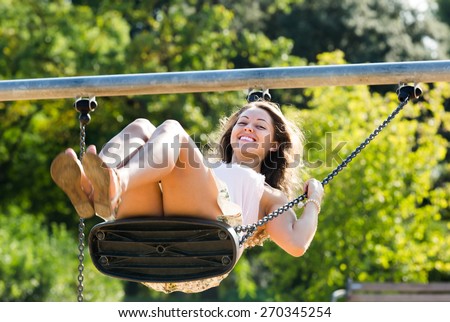 Young woman in skirt on swing in summer
