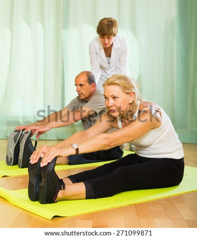 Medical staff at gym helping senior spouses to take correct position