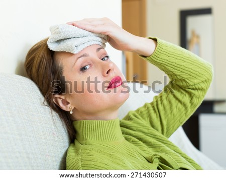 Sick  american woman with huge migraine holding wet towel on her head
