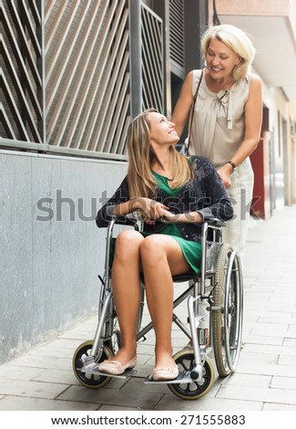Smiling female helping handicapped woman outdoor