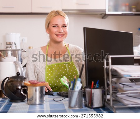 Female freelancer with PC, tea and sandwich at kitchen table