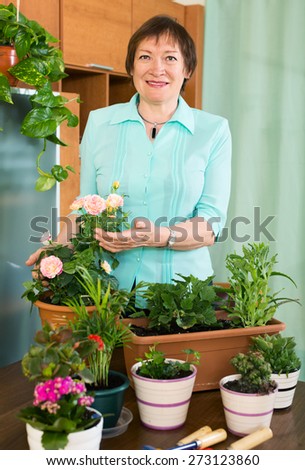Smiling mature woman and  her small garden  at home