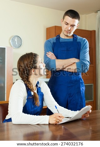 Unhappy workers in uniform reading financial documents at table