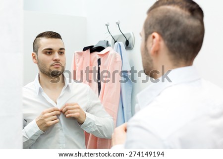 Portrait of cheerful young male with new clothes at fitting-room