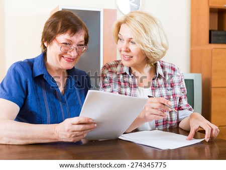 Two elderly women discussing work issues with documents in hand