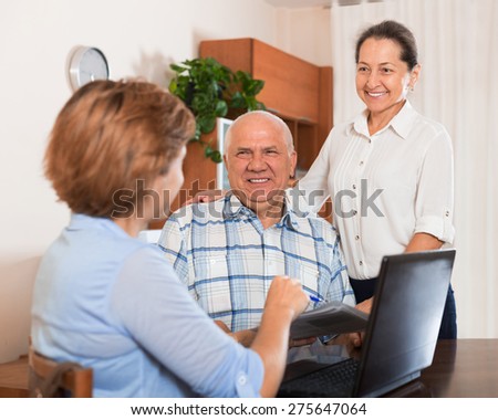 Mature couple answer questions of social worker with laptop in  office