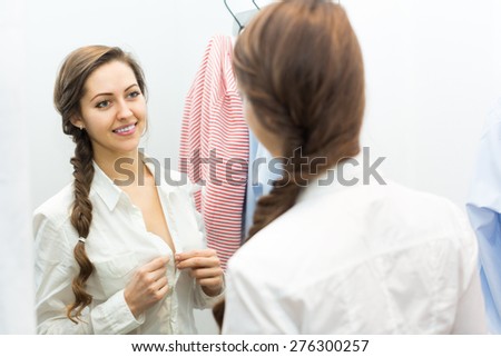 Positive young woman standing at boutique changing cubicle