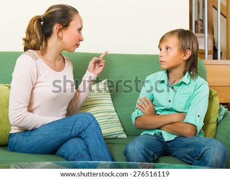 Angry mother scolding teenage son in home interior