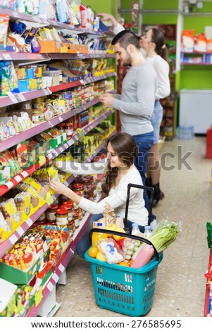 Adults people standing near shelves with canned goods at shop