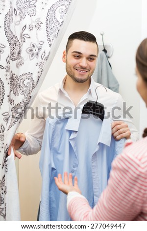 Positive and smilimg young spouses standing at boutique changing cubicle