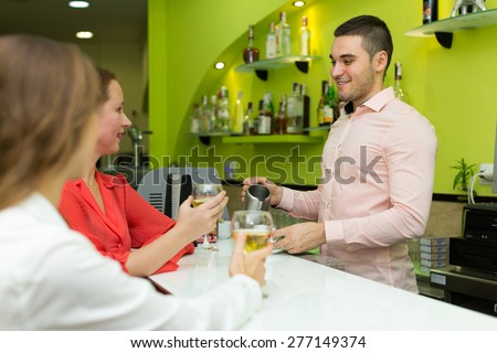 Two female friends chatting and drinking wine at the bar