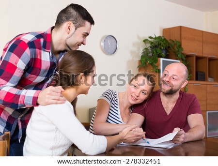 Two couples discussing terms of insurance company and smiling