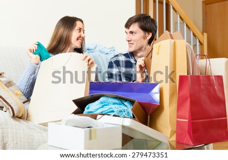 Smiling guy and girl discussing purchases in home