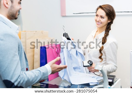 Beauty store clerk serving purchaser at cash register desk