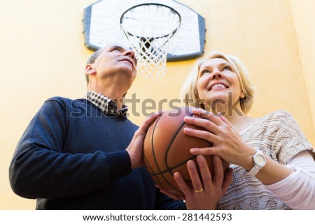 Happy smiling active couple of pensioners playing basketball in patio