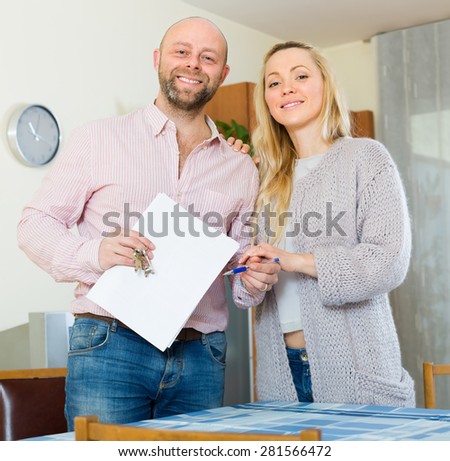 Positive smiling young couple with contract for buying apartment and keys