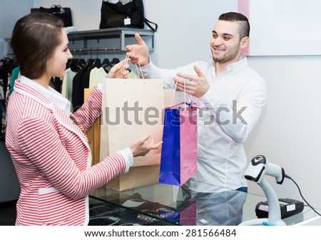 Positive store clerk serving purchaser at cash register desk
