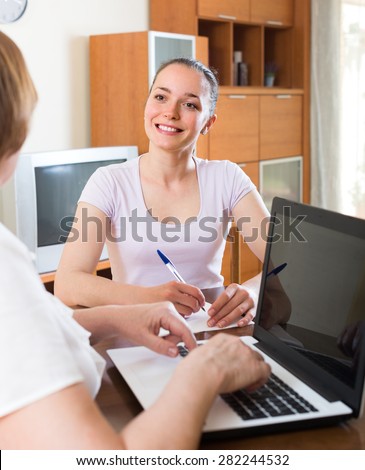 Smiling woman answer questions of social worker with laptop at table