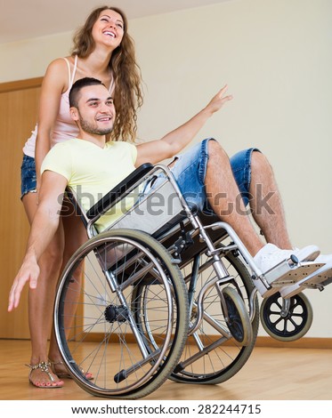 Happy friends with smiling young man on wheelchair in playful mood