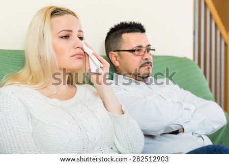 Sad man and unhappy crying young woman having conflict at home