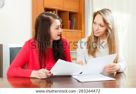 serious women looking financial documents at table in home or office interior