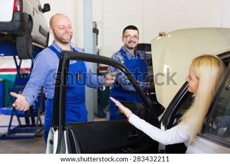 Service crew and satisfied girl driver standing near car and smiling indoor. Focus on man