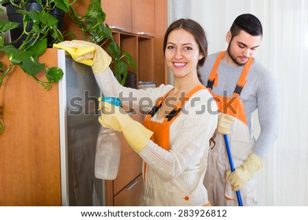 Portrait of smiling professional cleaners team with equipment at the work in client house