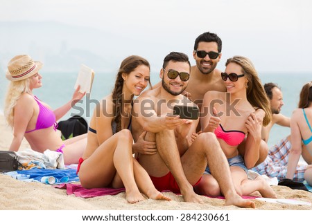 Young friendly people making mutual photo at sandy beach