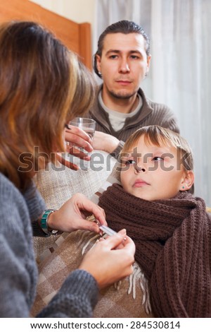 Parents taking temperature of son at home