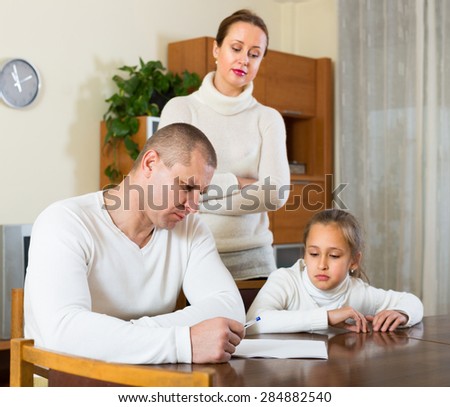 Sad family with preschooler daughter solving financial problems at the table at home