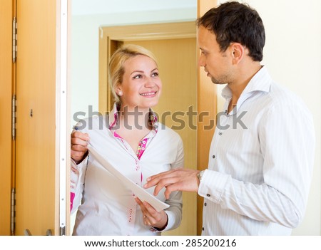 Beautiful woman conducting  survey among people at door. Focus on the woman