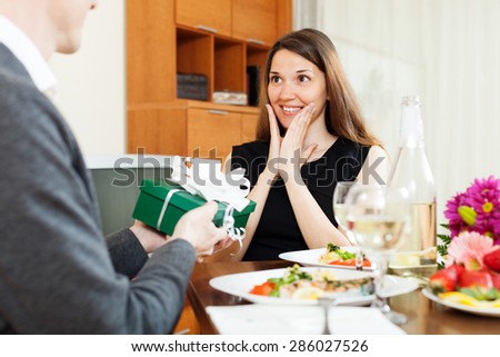 Man giving present to young woman during romantic dinner