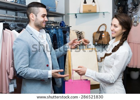 Store clerk serving purchaser at fashionable apparel store