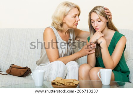 Mature mother consoles sad daughter at home