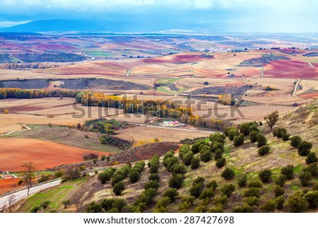 View down the hill at agricultural fields under cloudy sky