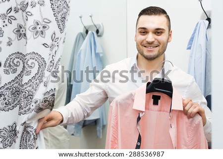 Positive smiling young man standing at boutique changing cubicle