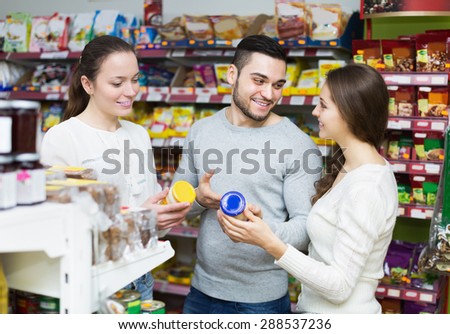 Cheerful young adults choosing tinned food at supermarket