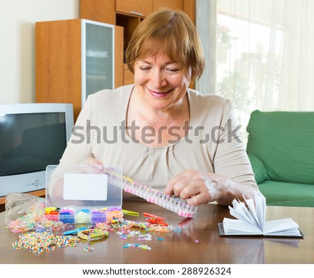 Mature woman makes bracelets with elastic rainbow loom bands