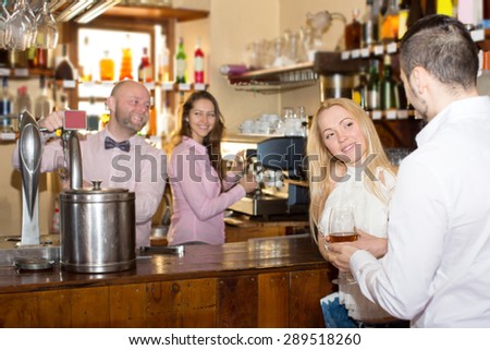 Smiling couple waiting for table in restaurant and drinking wine at tavern. Focus on the woman