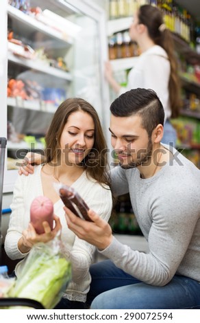 Happy customers standing near the fridge with meat products