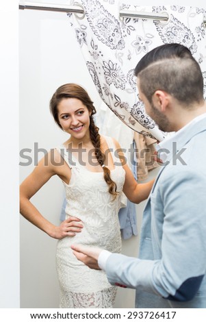 Portrait of happy smiling young couple with new apparel at fitting-room in clothing store