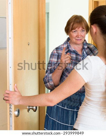 Senior aggressive woman have conflict with neighbour at the doorway