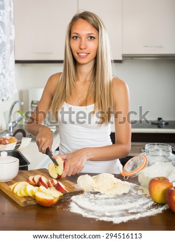 Young housewife cooking apple pie at domestic kitchen
