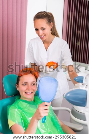 Happy smiling female patient whitening  teeth in the dental clinic